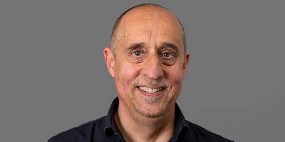 Portraitbild von Prof. Dr. Peter Schwehr, ein Mann mit hoher Stirn und sehr kurz geschorenem Haar und mittleren Alters lächelt in die Blickperspektive